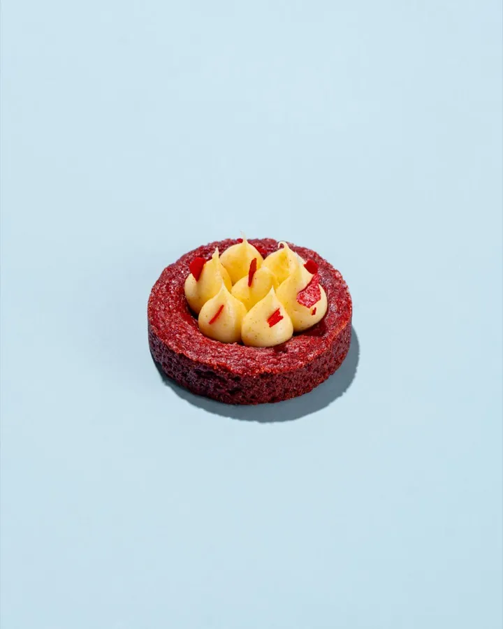 Red Flag cookie: red velvet cookie base with white chocolate chips, brown butter cream cheese frosting, red tuile